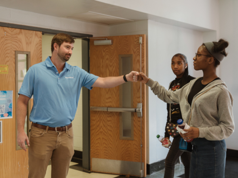 Students receiving fist bump from ExxonMobil volunteer